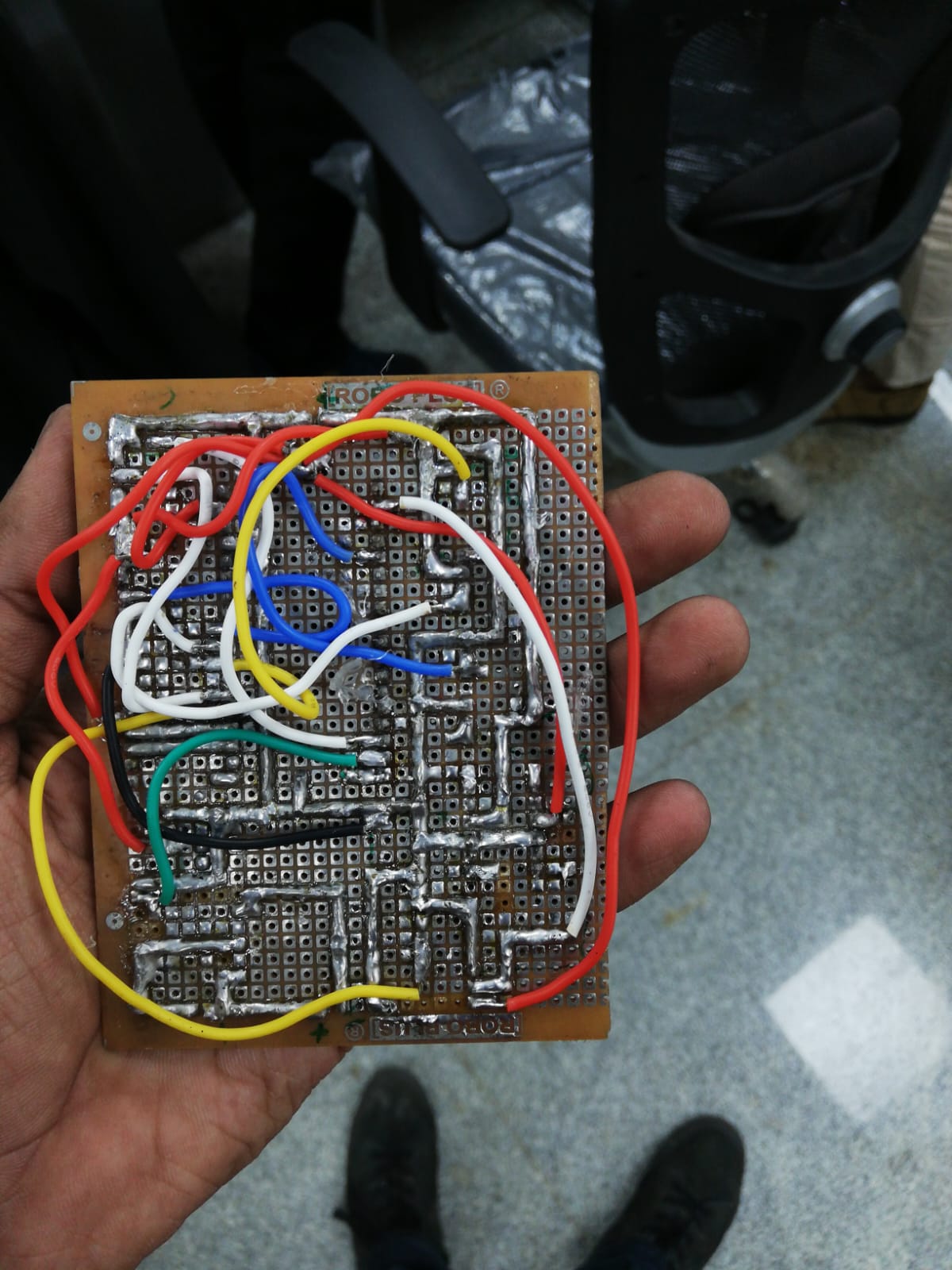 Hand-soldered protoboard backside showing power rail routing and signal traces
